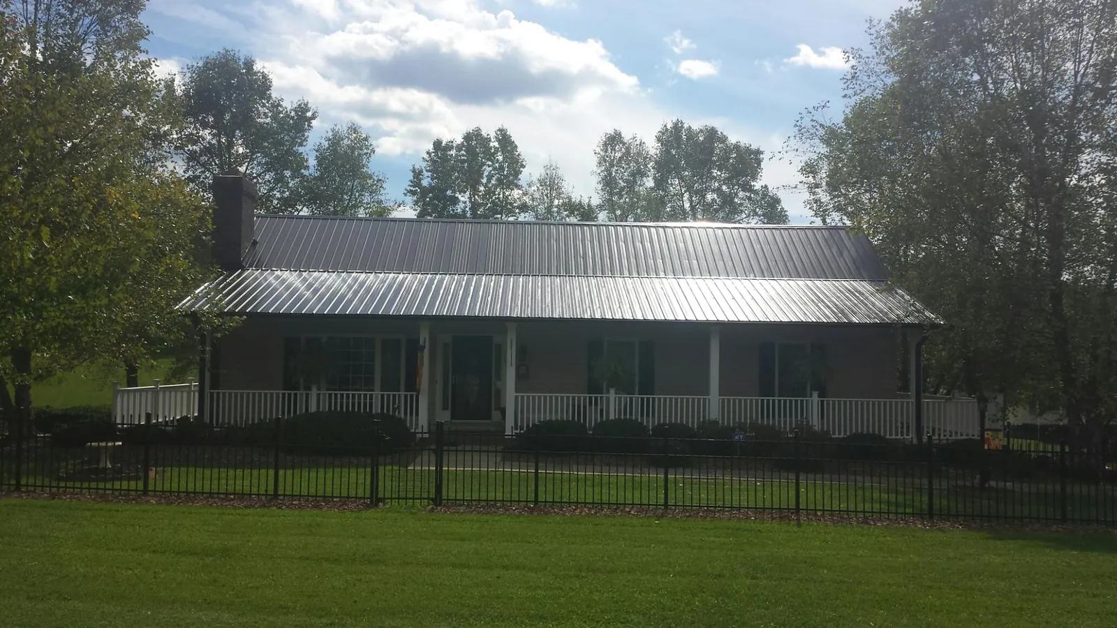 Gray metal roof on a brick ranch with a full width front porch — Gutter Guard Installation work by our crew in Fairmount
