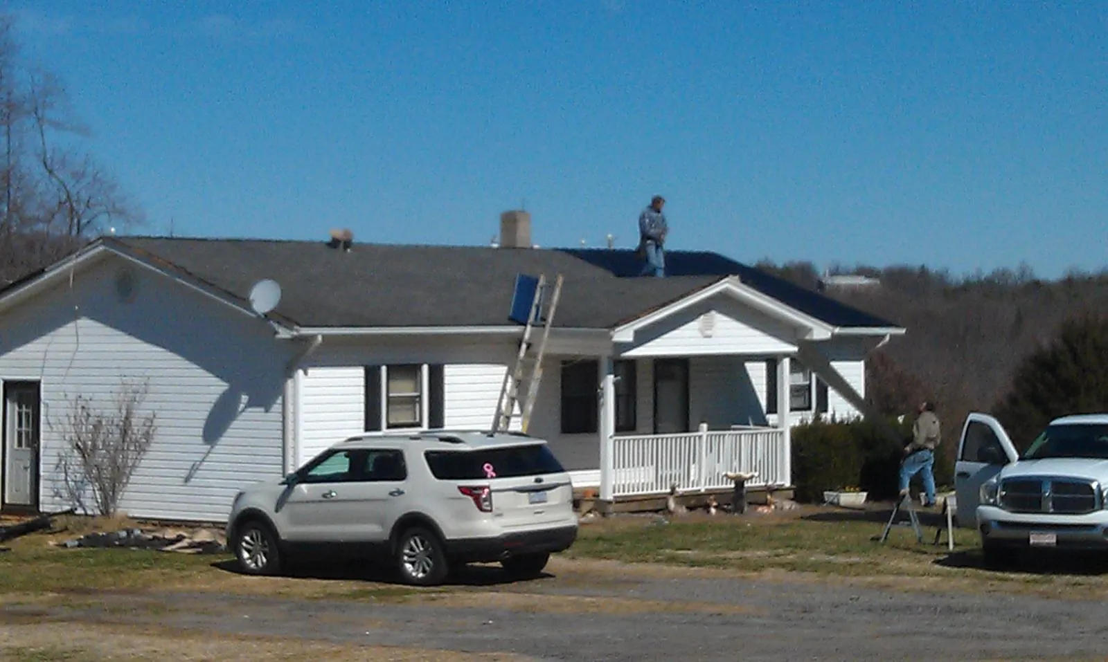 Roofers stripping shingles from a white ranch house roof in Fairmount